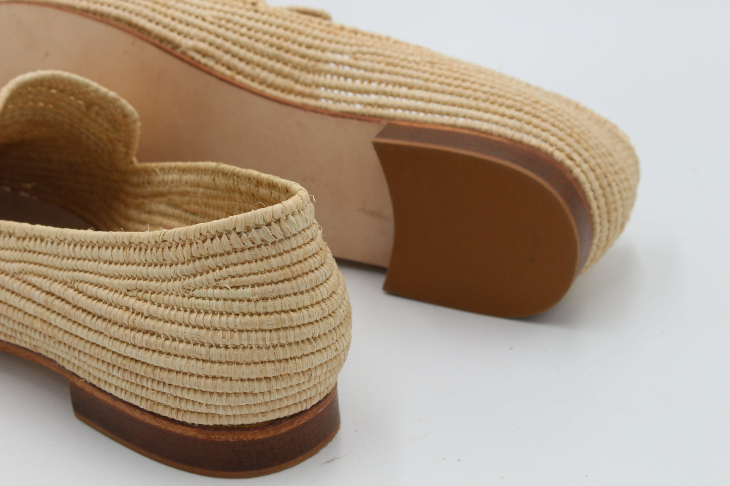 Beige woven shoes with brown soles on a white background