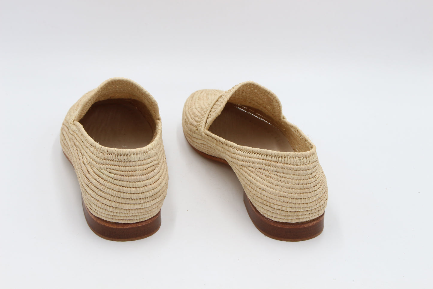 Pair of beige woven shoes with brown soles on a white background