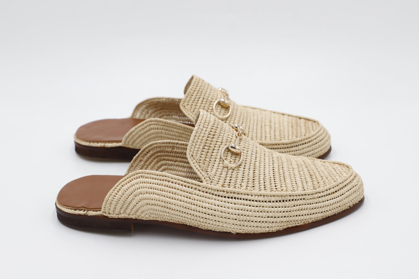 Pair of beige woven slippers on a white background