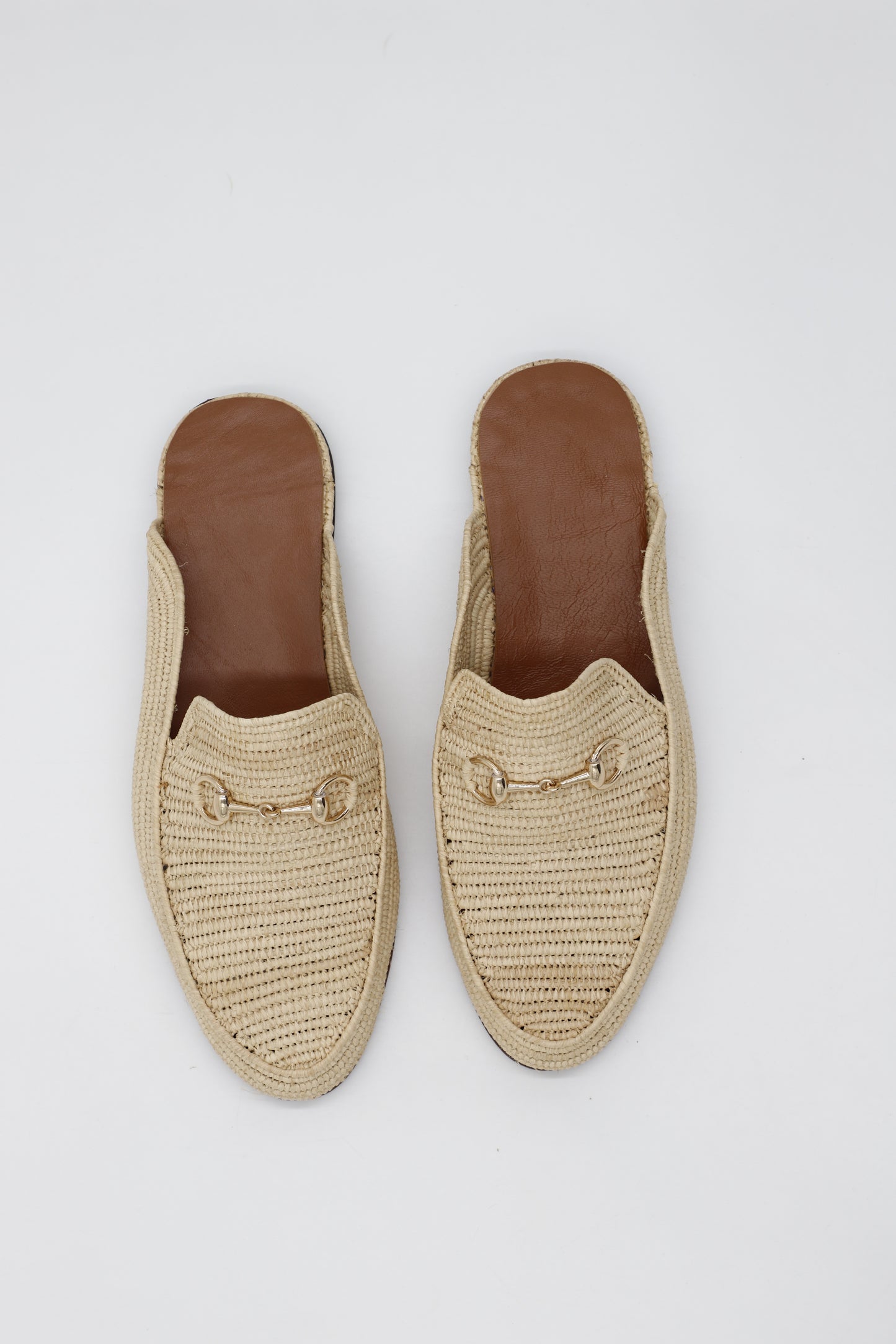 Pair of beige espadrille shoes with brown soles on a light gray background