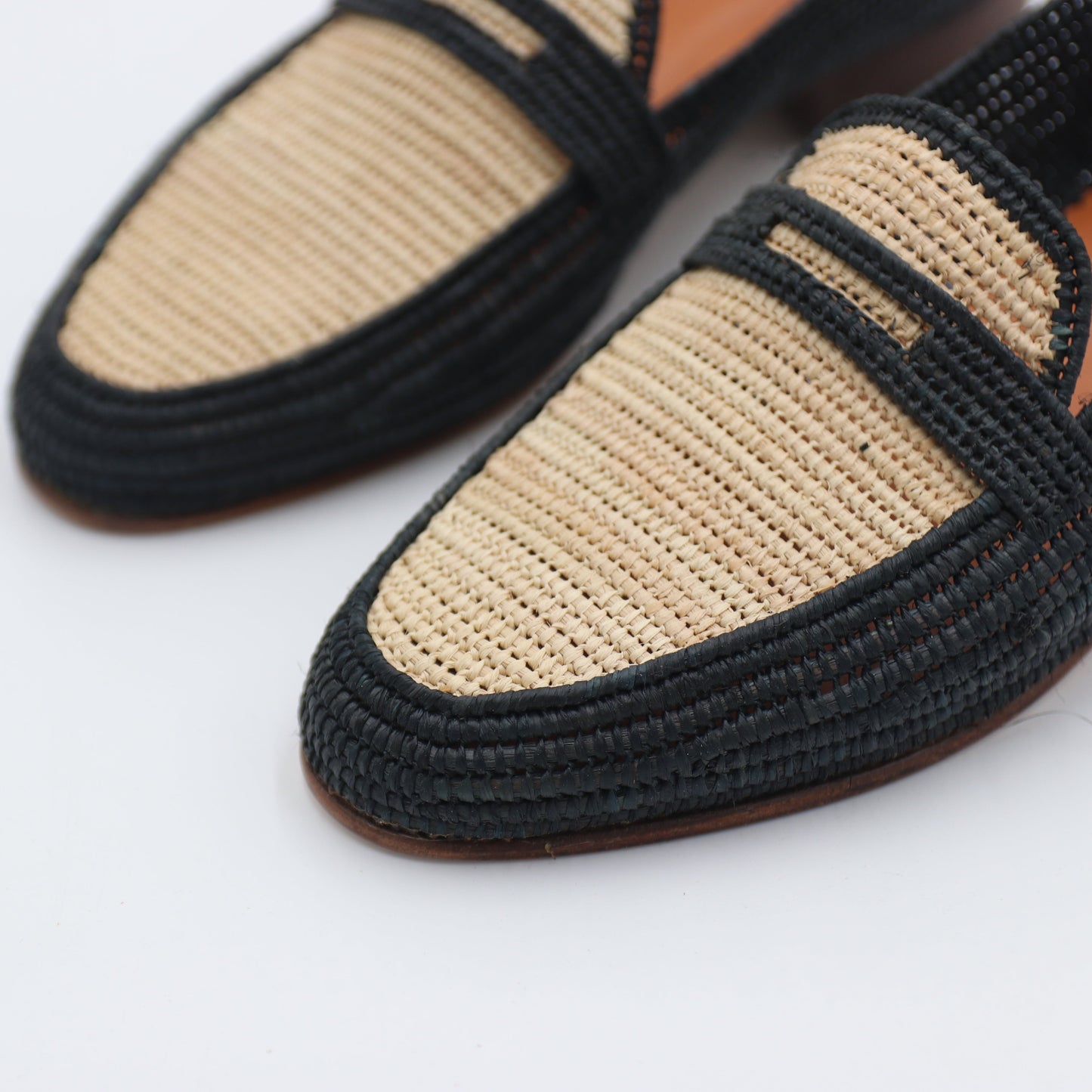 Pair of black and beige loafers on a white background