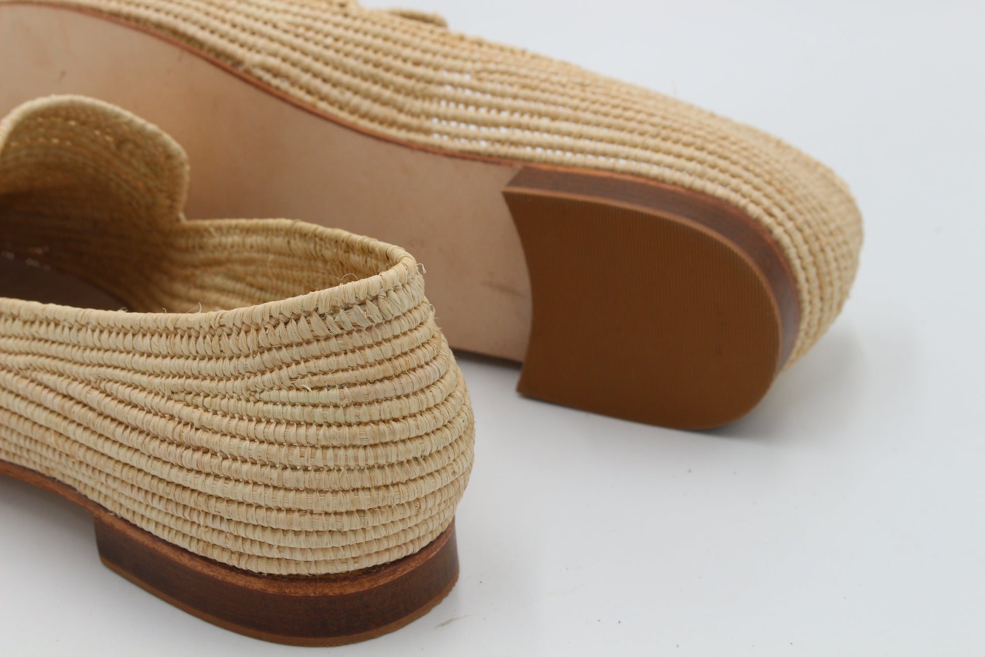Beige woven shoes with brown soles on a white background