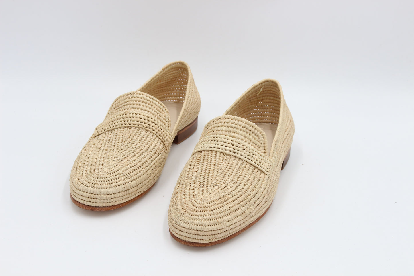 Pair of beige woven loafers on a white background