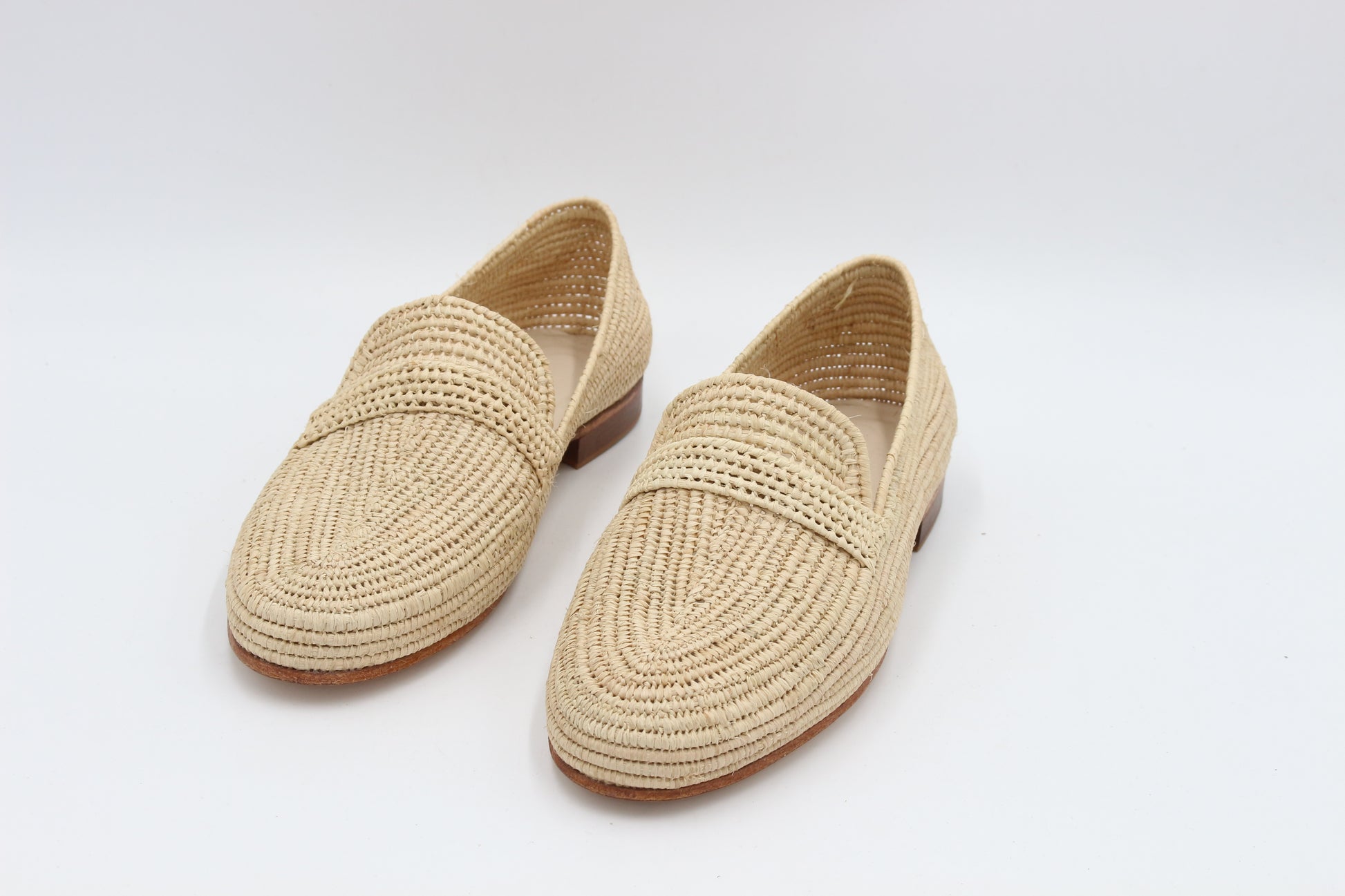 Pair of beige woven loafers on a white background