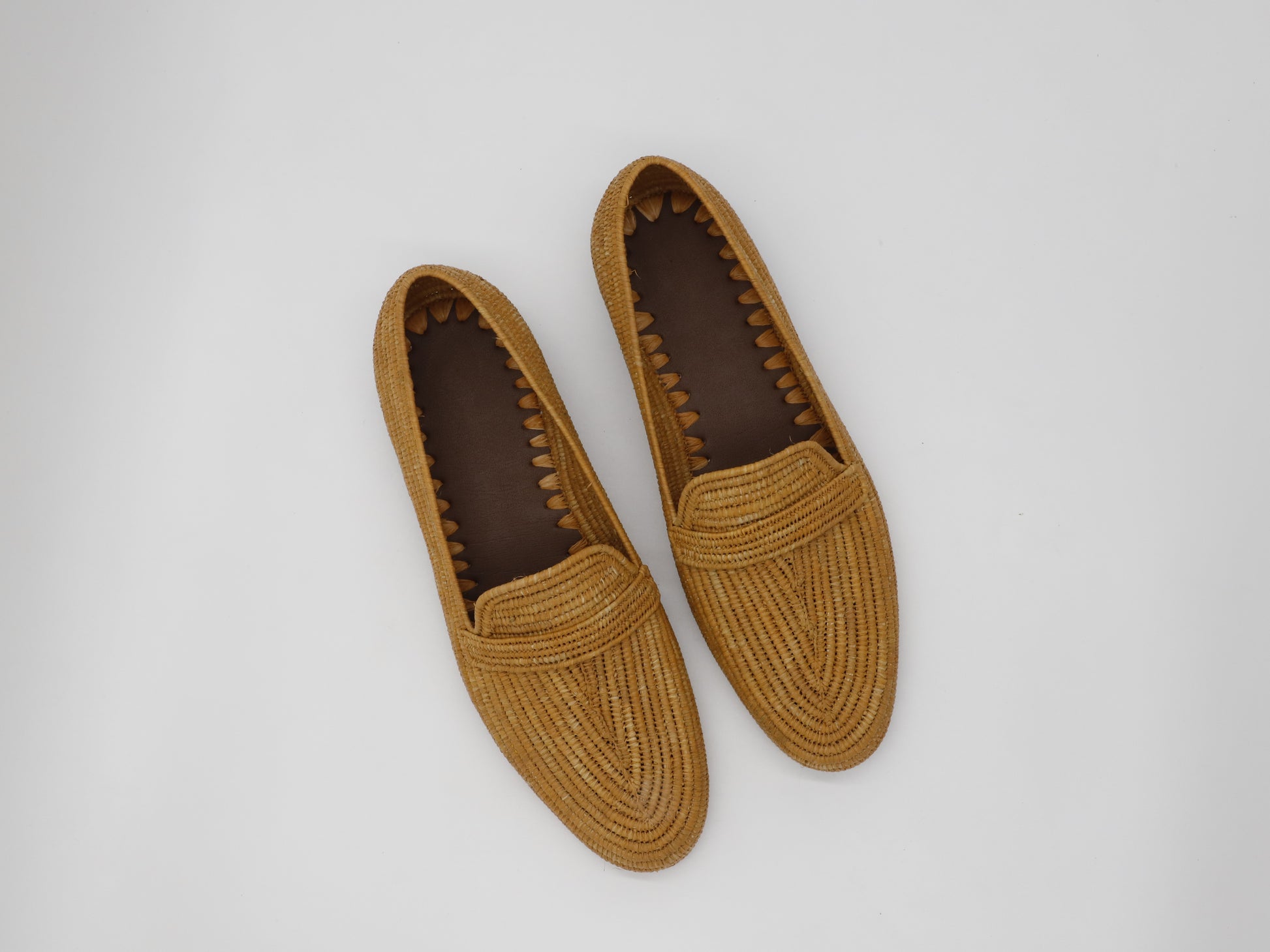 Pair of brown woven loafers on a light gray background