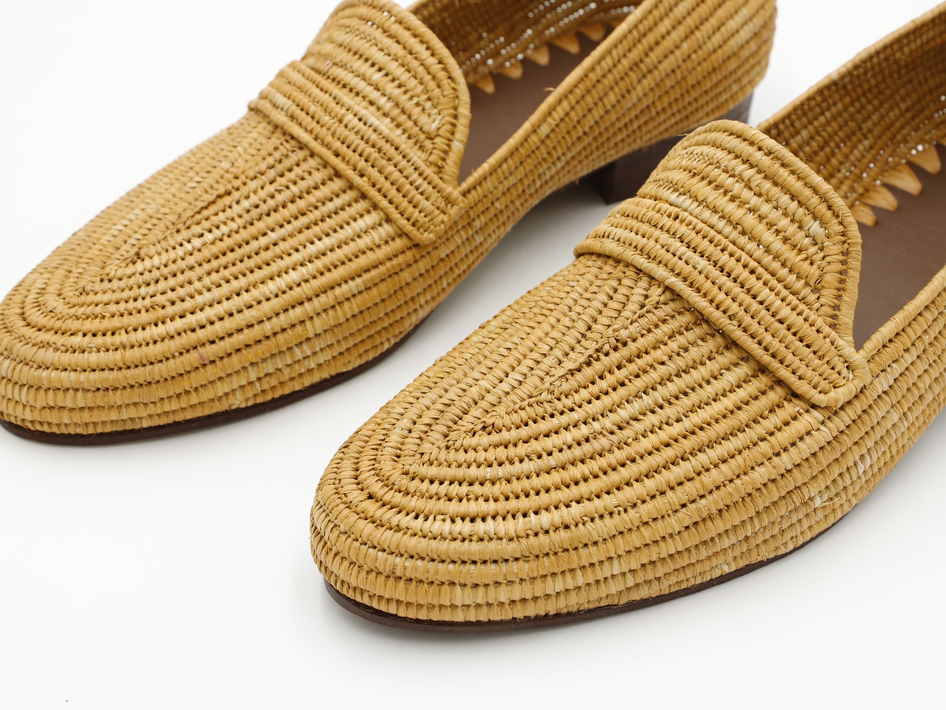 Pair of woven yellow loafers on a white background
