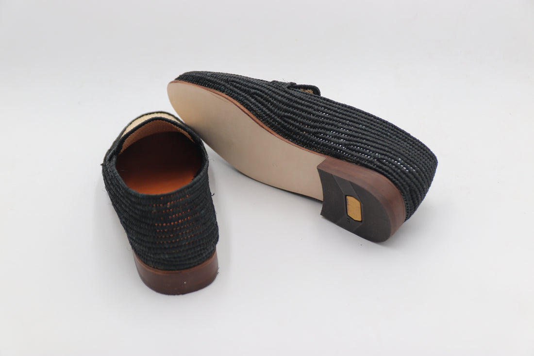 Black textured shoe with brown sole on a white background