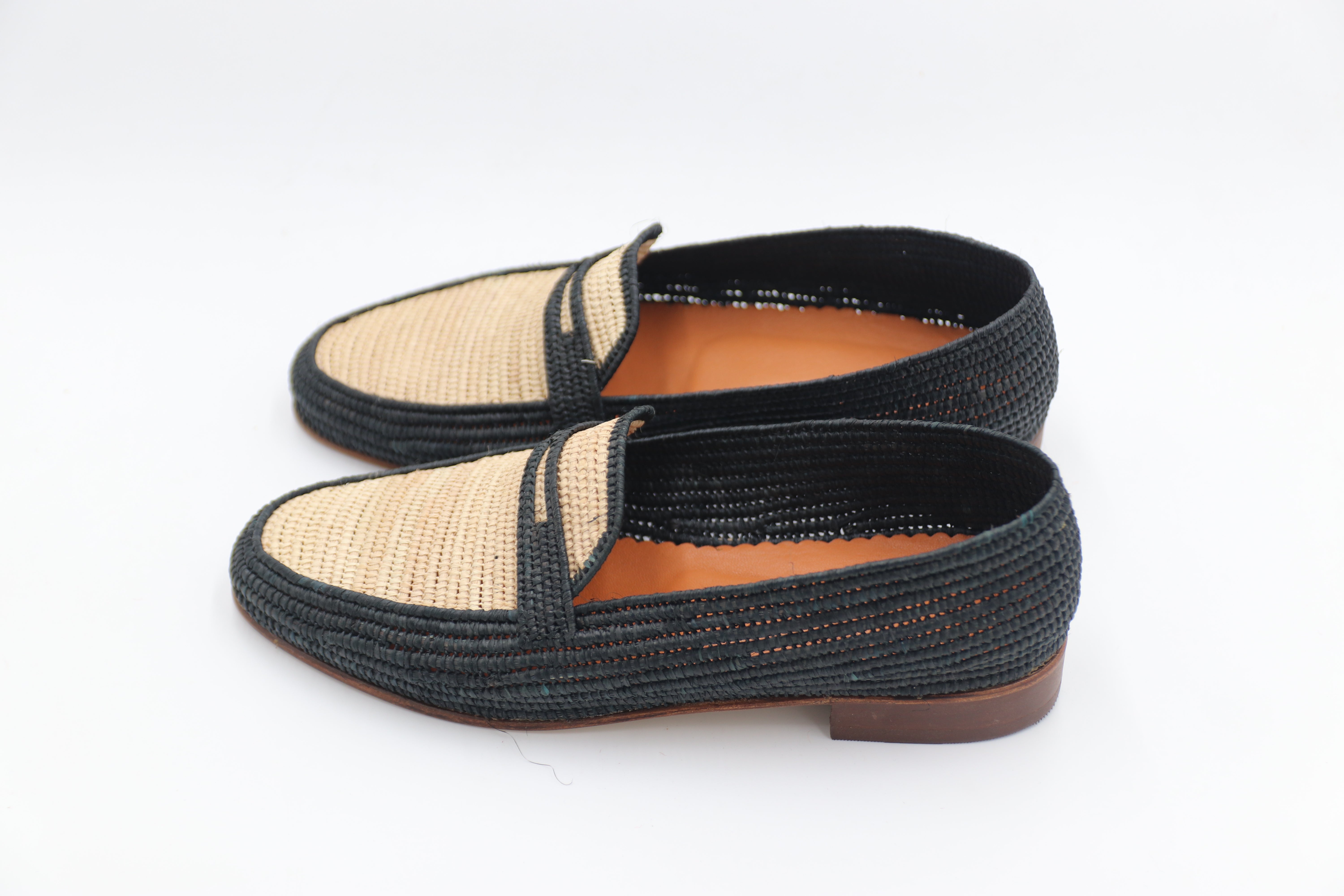 Pair of black and beige woven shoes on a white background