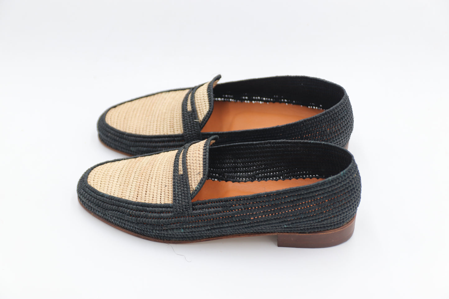 Pair of black and beige woven shoes on a white background