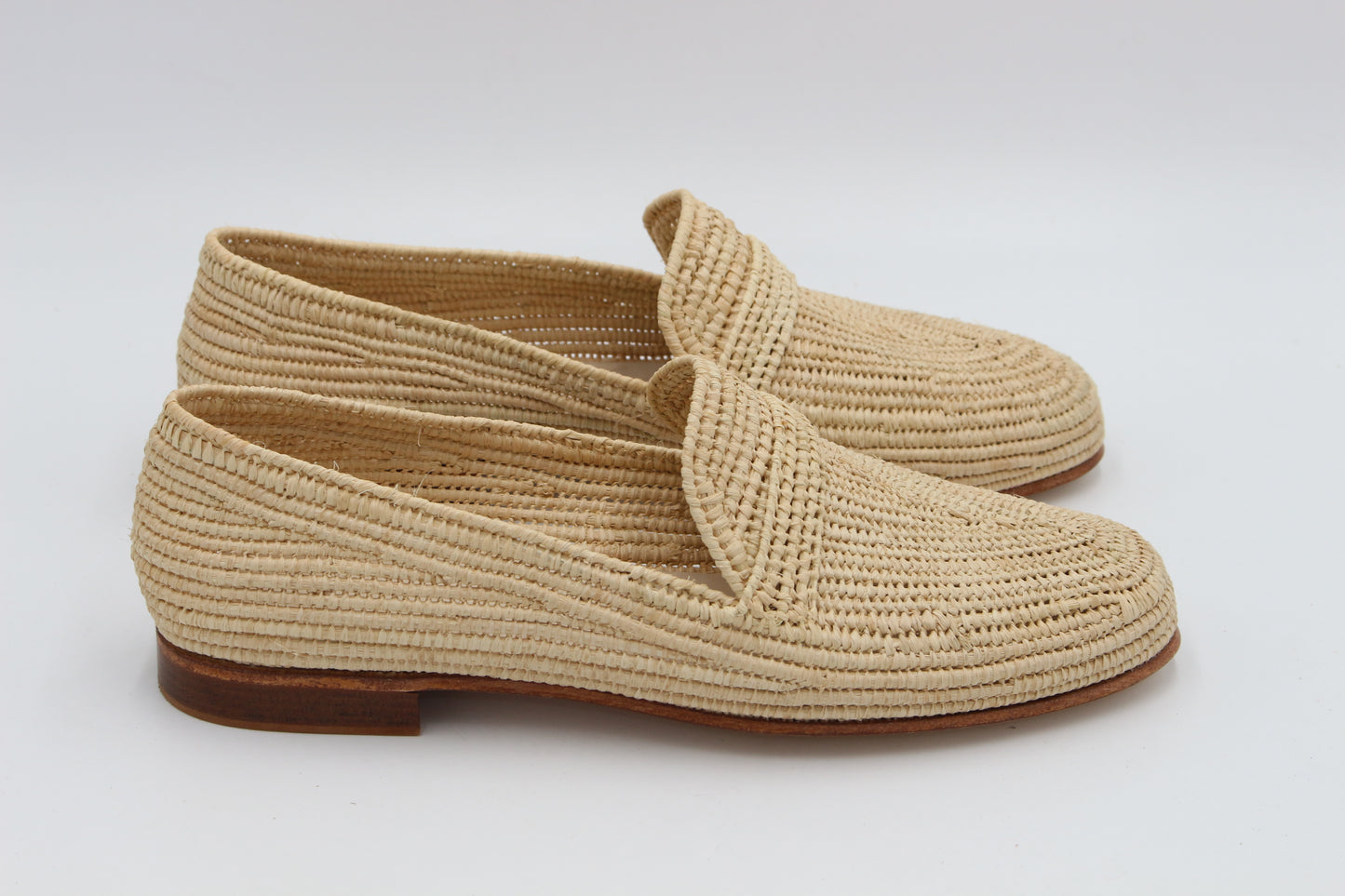 Pair of beige woven shoes on a white background