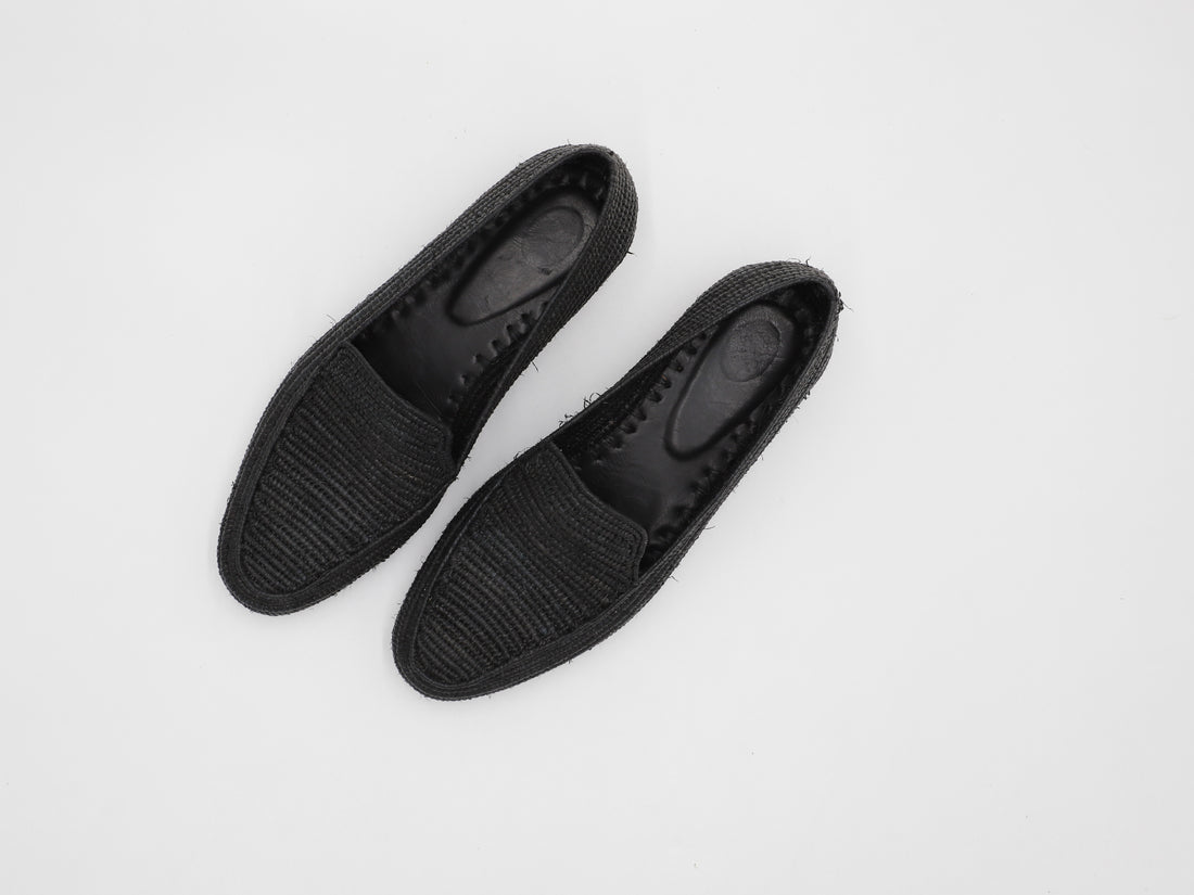 Man walking on beach wearing breathable summer raffia shoes with ocean in background